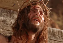 Close-up of Jesus Christ wearing a crown of thorns during crucifixion, a scene from the Gospel of John film.